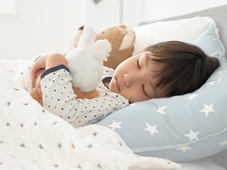 ぬいぐるみを抱いて眠っている男の子の画像です。クリックすると該当ページに移動します。