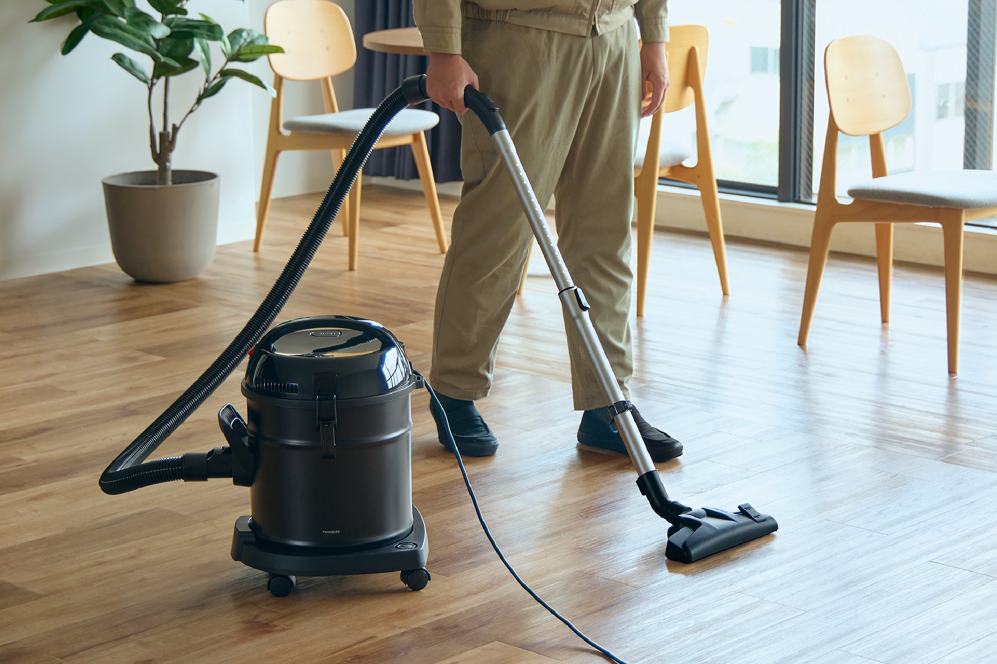 作業着を着た男性が大容量クリーナーで室内を掃除している写真